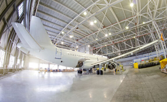 Passenger airplane on maintenance of engine, fuselage and on auxiliary power unit. check repair in airport hangar. Aircraft view tail, with open luggage compartment